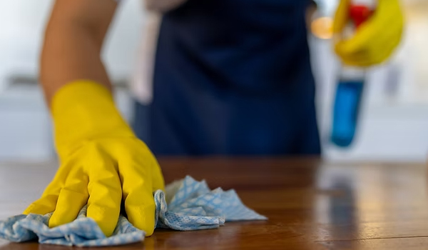 cleaners wiping a glass surface with a spray and cloth.