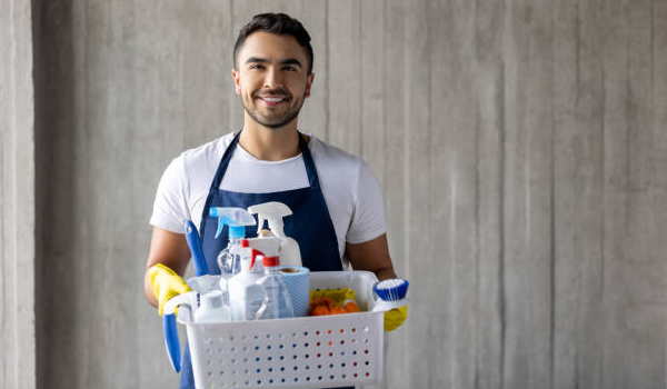 Smiling cleaners holding a basket of professional supplies