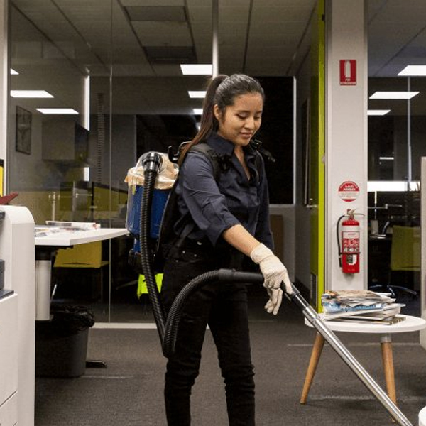 Commercial Cleaners buffing floors and wiping office desks.